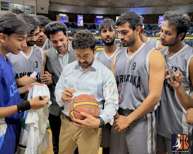 Aamir Khan signing basketball while interacting with IB Sports Academy players and Coach Ishwar Bhati