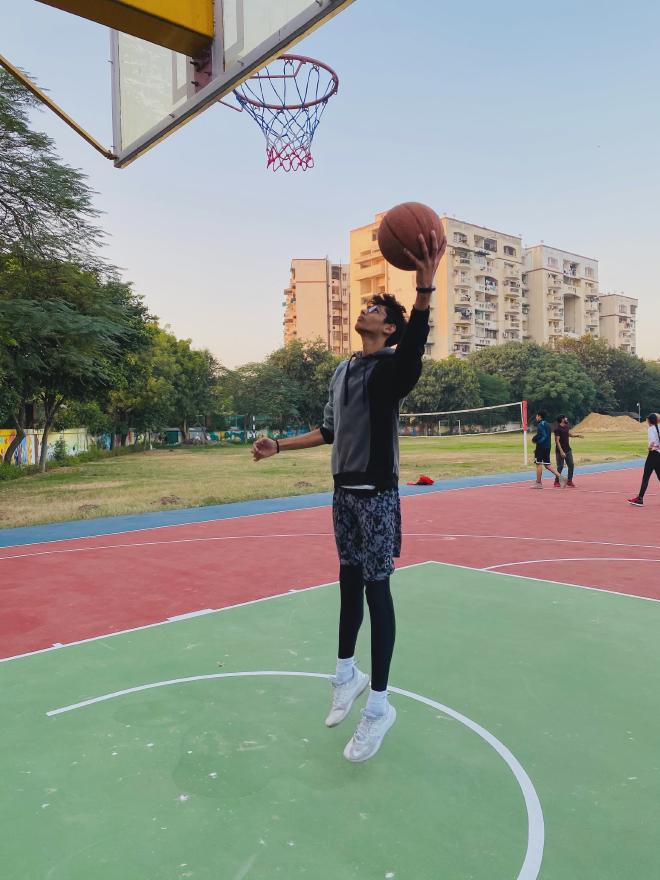 Tall student athlete dunking basketball at IB Sports Academy. He can reach basket while standing.